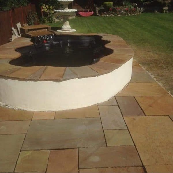 Sandstone patio with a curved, rendered raised pond