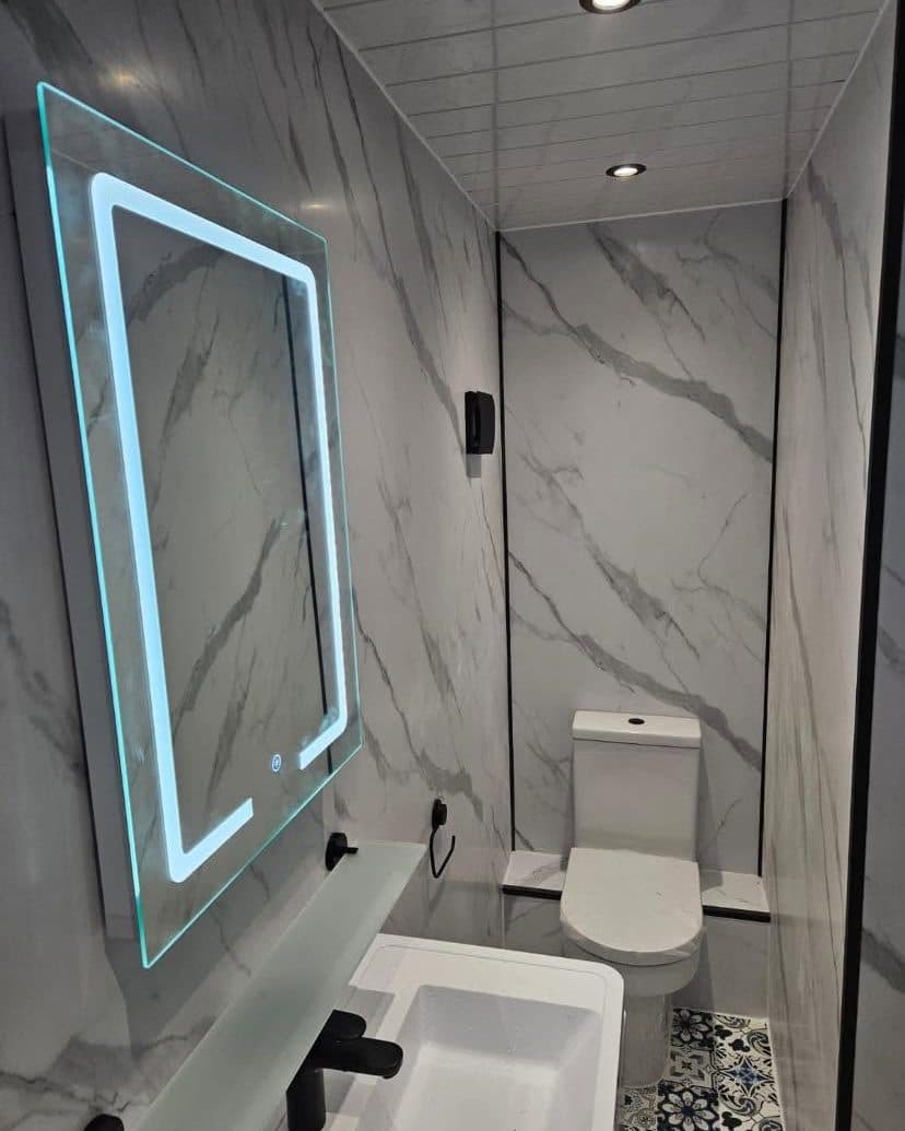 Marble-effect shower room with an illuminated mirror and close-coupled toilet